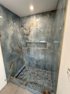Luxury bathroom remodel with gray marble tile walls and built-in shower niche by Cornerstone Flooring in Orlando Area