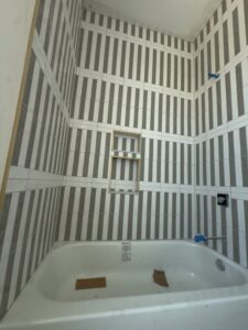 Bathroom remodeling in progress with bathtub installed and vertical wall tile spacers for porcelain tile installation in Orlando, Florida.